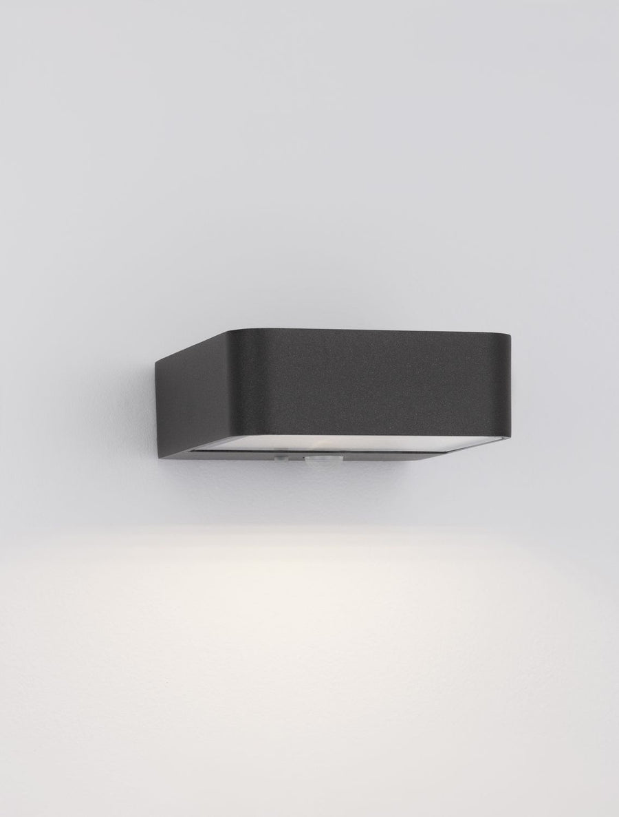 Luminaire mural allumé diffusant un halo lumineux blanc vers le bas
