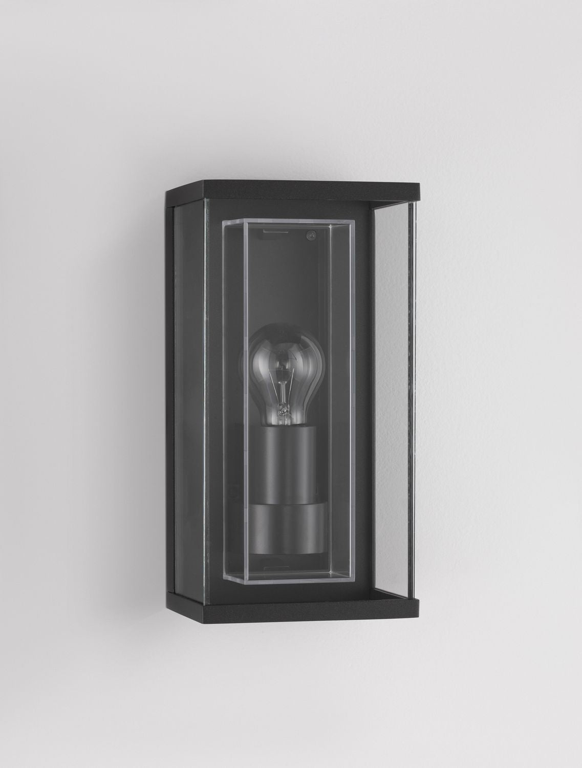 Vue de trois quarts du boîtier anthracite posé contre un mur gris clair