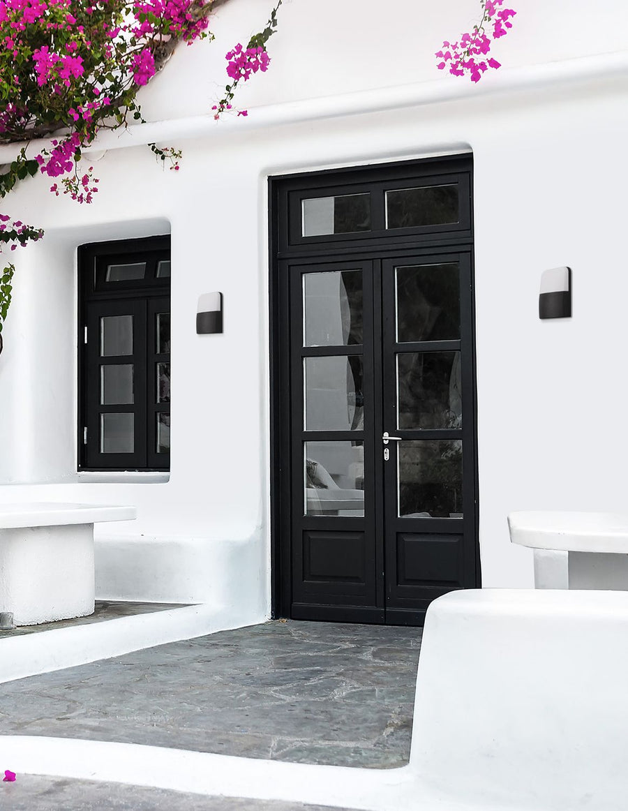 Applique murale noire et blanche fixée sur mur blanc, près de portes vitrées