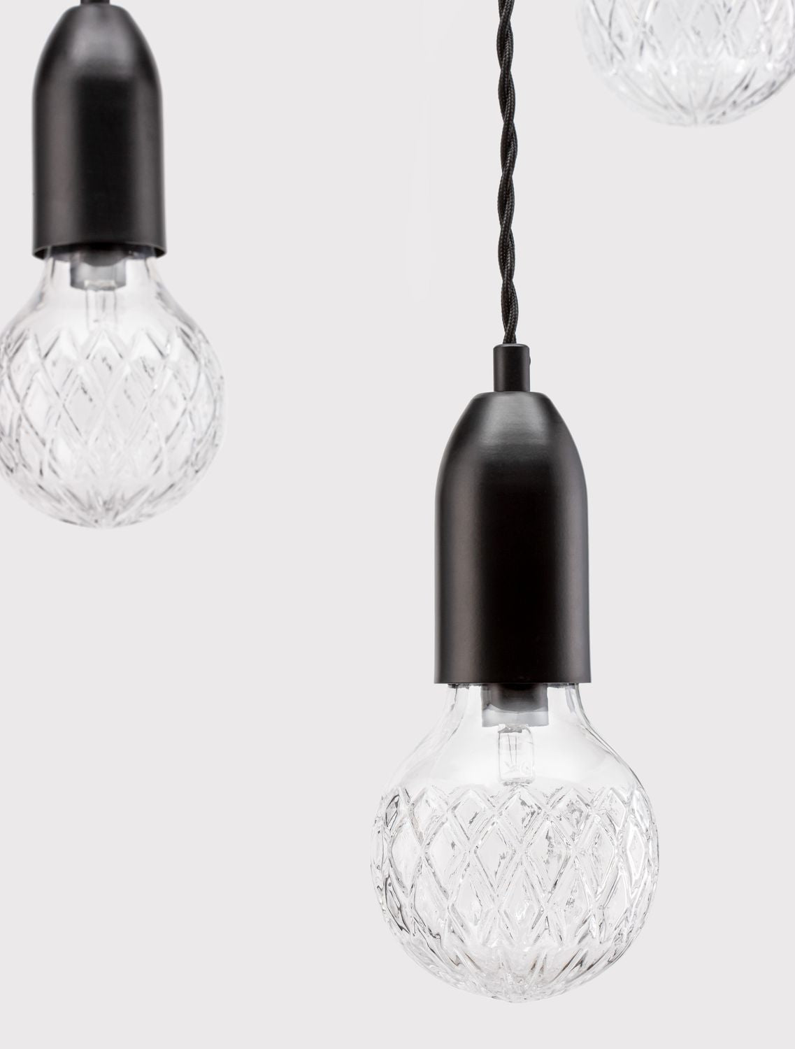 Détail rapproché d'une douille noire cylindrique et de l'ampoule en verre texturé