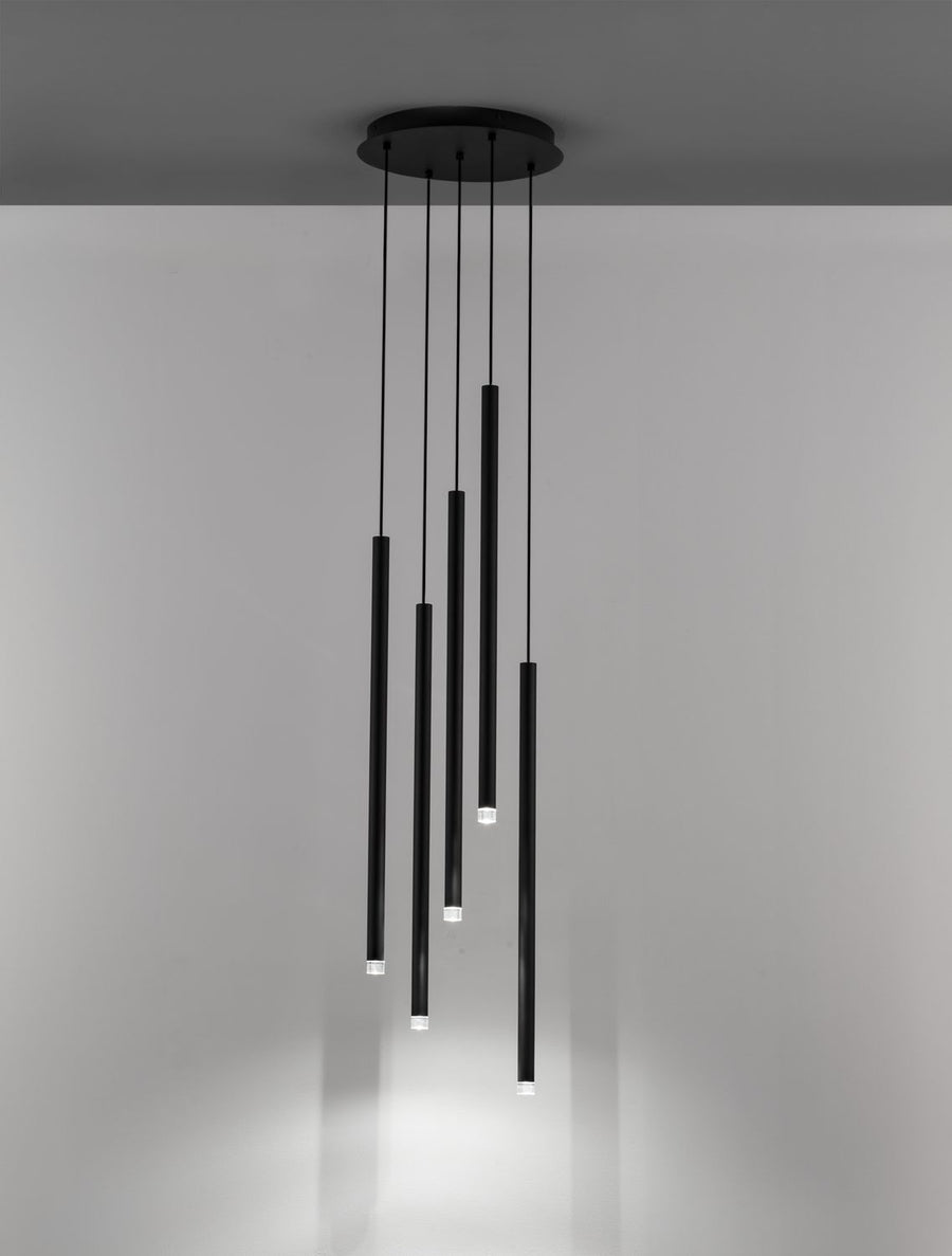 Suspension noire allumée au plafond, cinq tubes lumineux suspendus éclairant une pièce sombre.