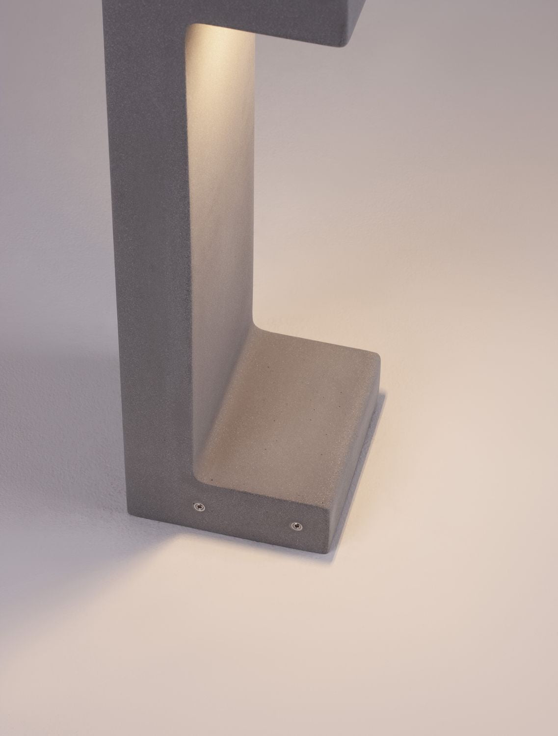 Détail rapproché de la base, de la texture grise et des vis de fixation.