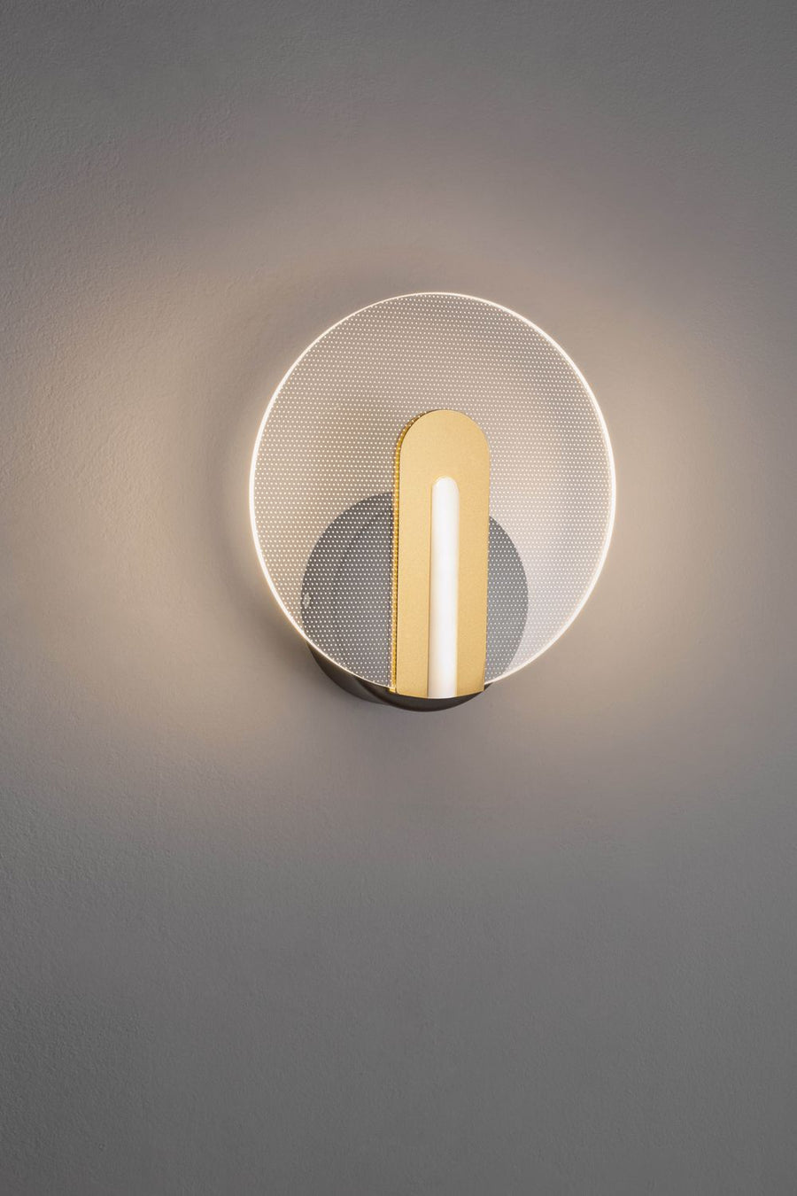 Applique murale allumée, halo lumineux sur mur gris, face avant du produit.