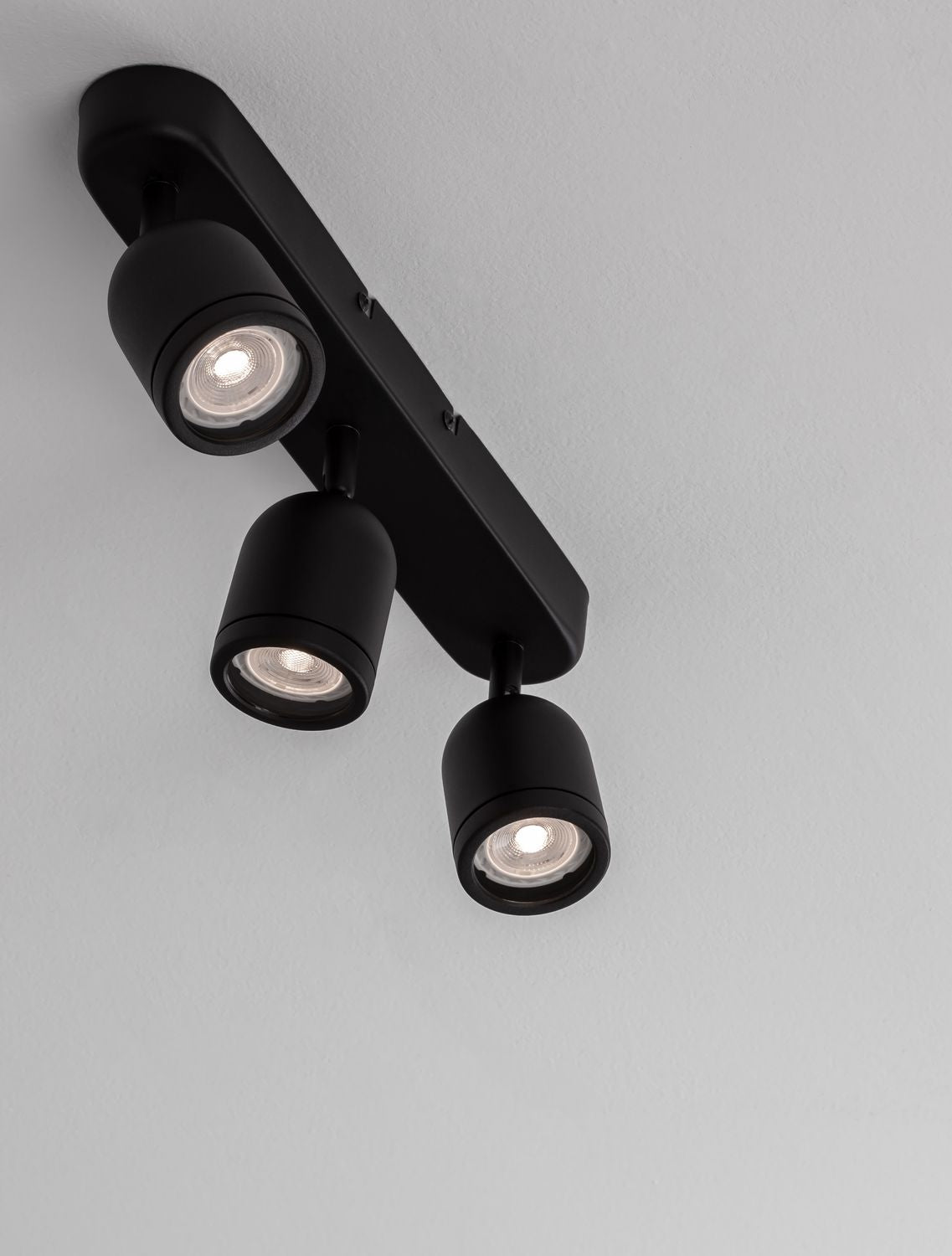 Vue en plongée montrant trois spots cylindriques allumés et orientables sous la barre