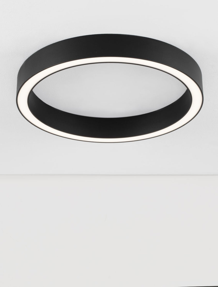Détail rapproché du luminaire noir, anneau LED blanc en périphérie et diffuseur central.