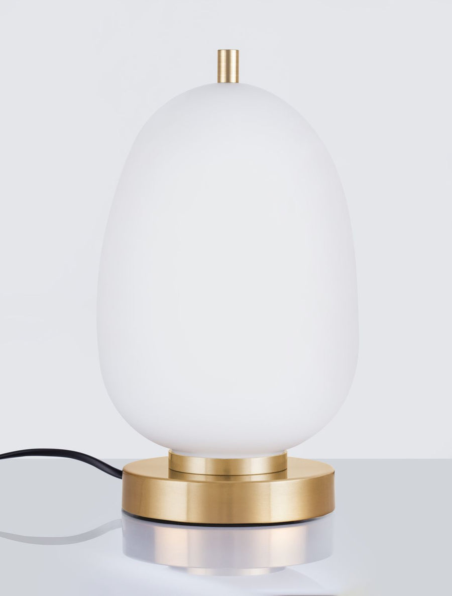 Détail du socle cylindrique en laiton brossé et du cordon noir, lampe éteinte