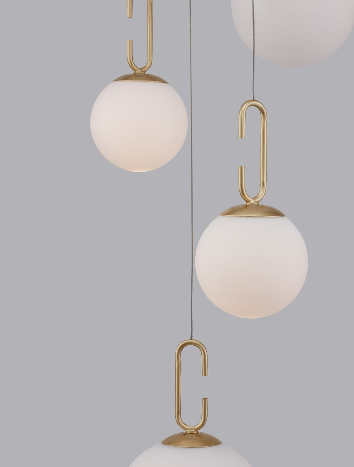 Gros plan sur les crochets dorés en forme de U tenant les globes de verre
