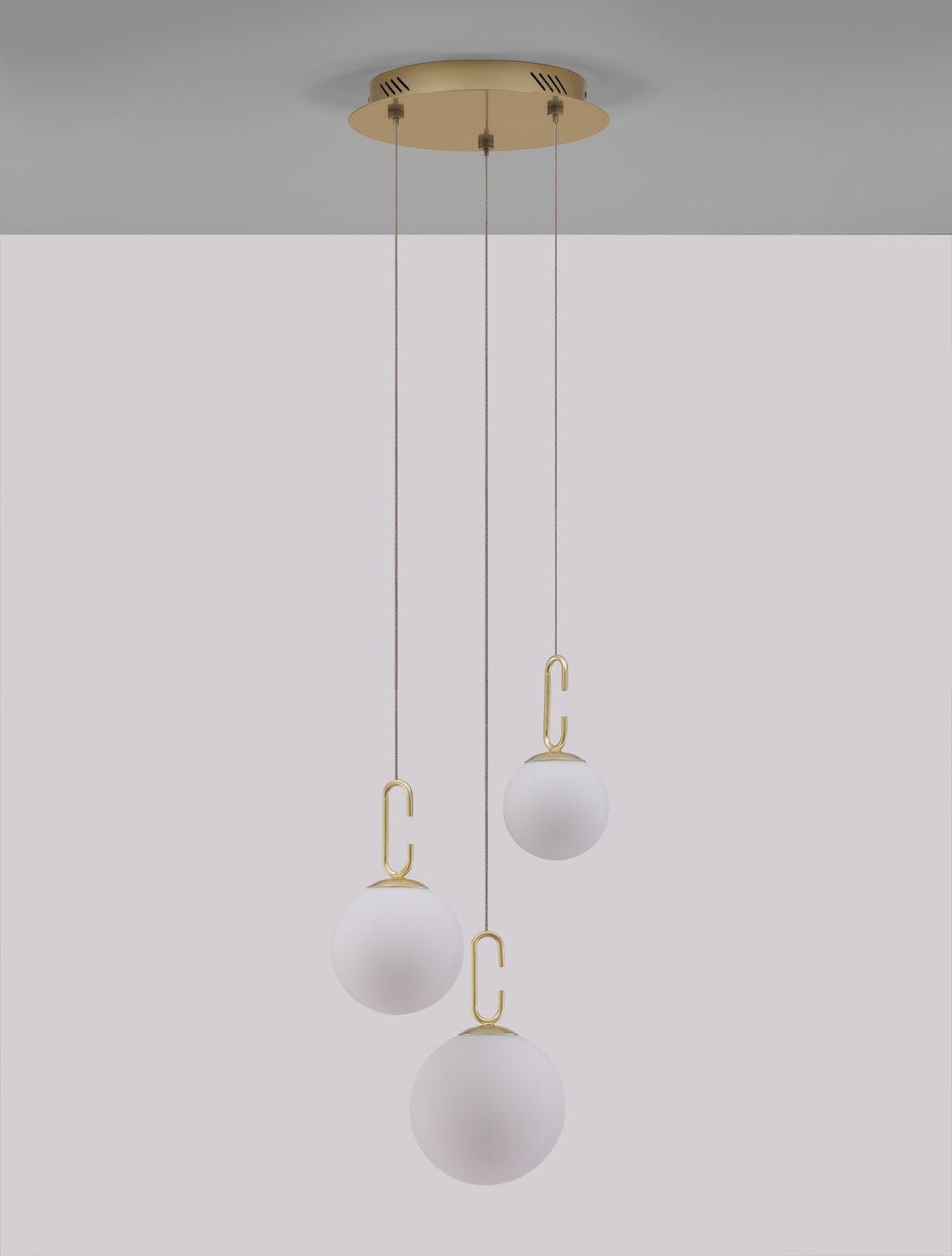 Suspension installée au plafond avec trois globes blancs suspendus par des câbles fins.