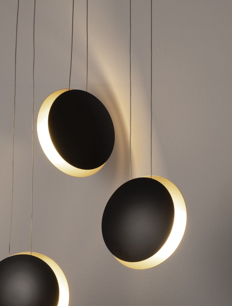 Luminaire allumé, halo doré projeté sur le mur derrière les disques noirs