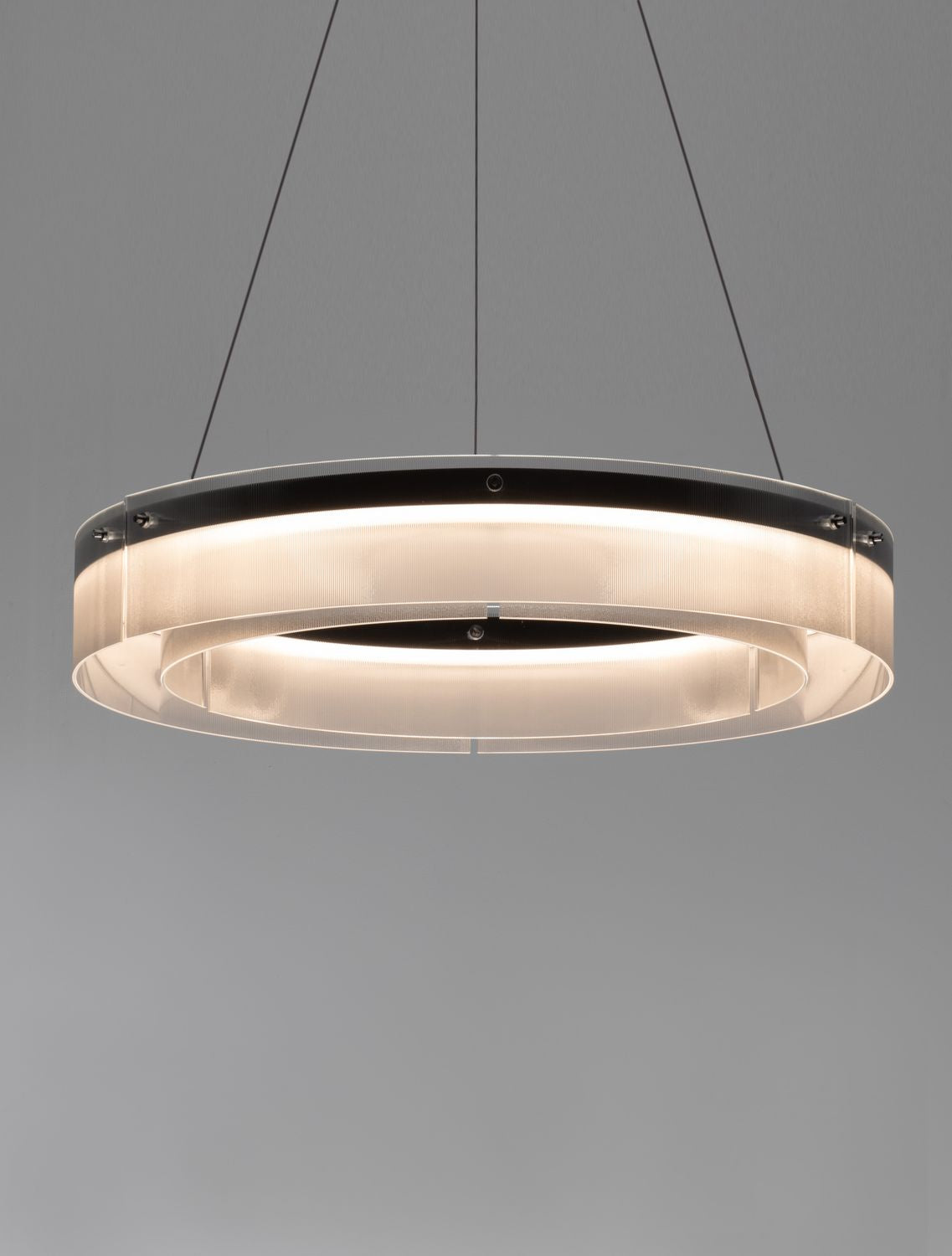 Vue en contre-plongée du luminaire allumé, anneau de verre et câbles fins
