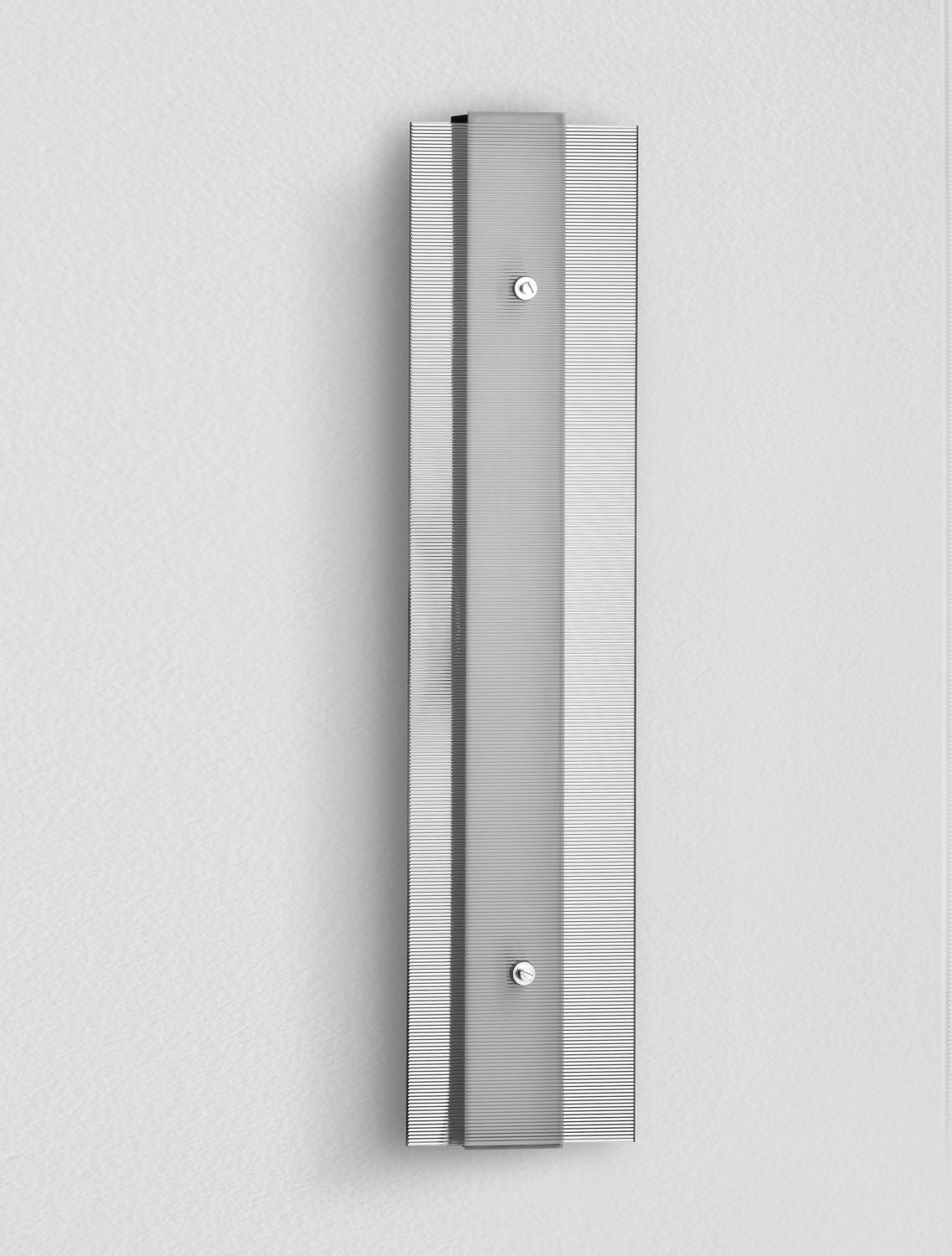 Vue de trois quarts sur mur blanc, applique allumée diffusant une lumière douce.