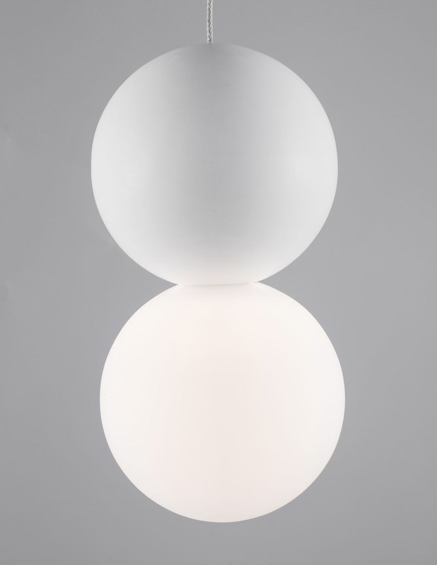 Détail des deux sphères en verre blanc sur fond gris, éclairage doux et diffus.