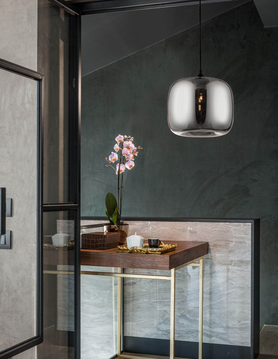 Suspension noire en verre fumé allumée dans un intérieur contemporain au-dessus d'une table