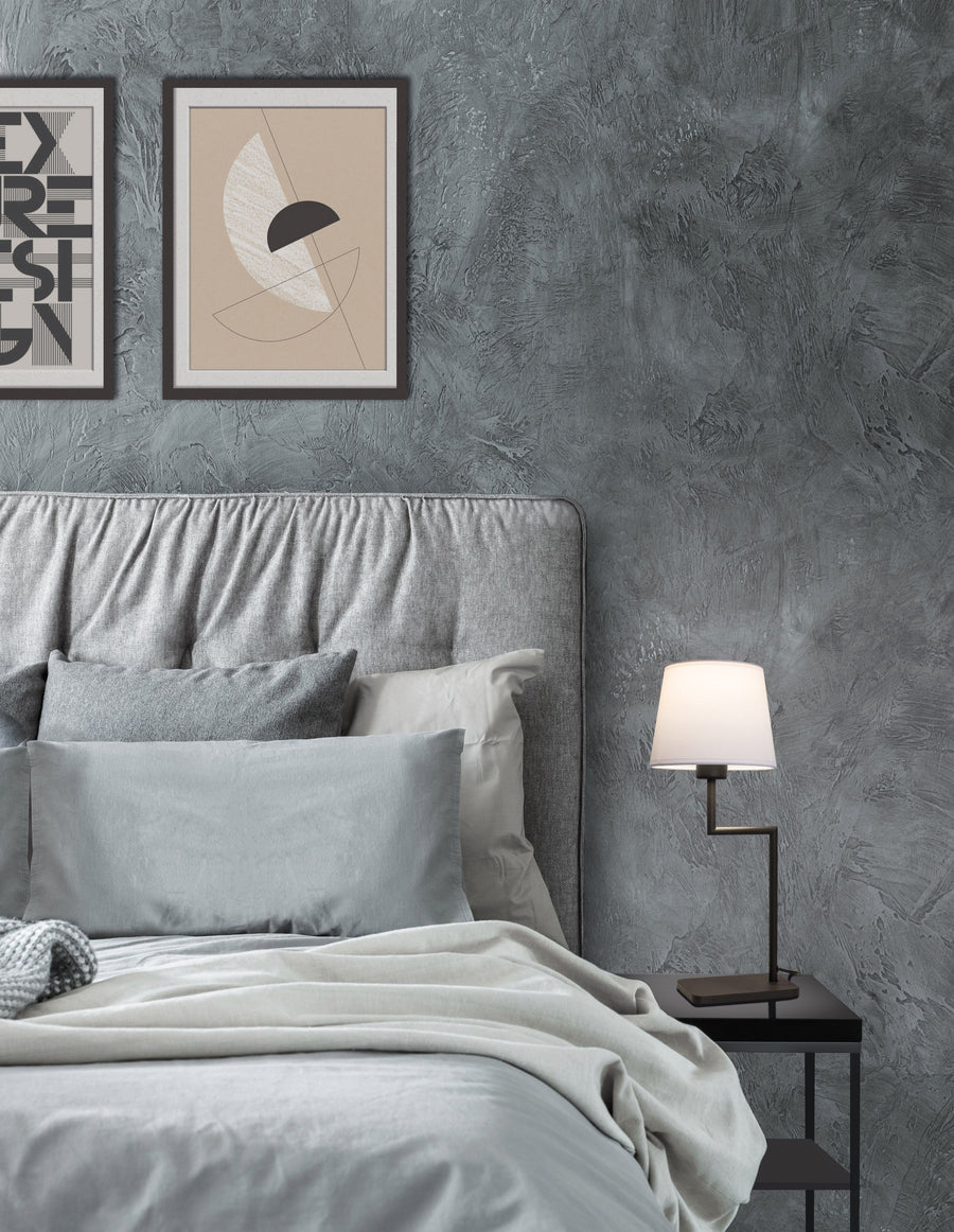 Lampe à poser noire allumée sur chevet, dans une chambre grise contemporaine.