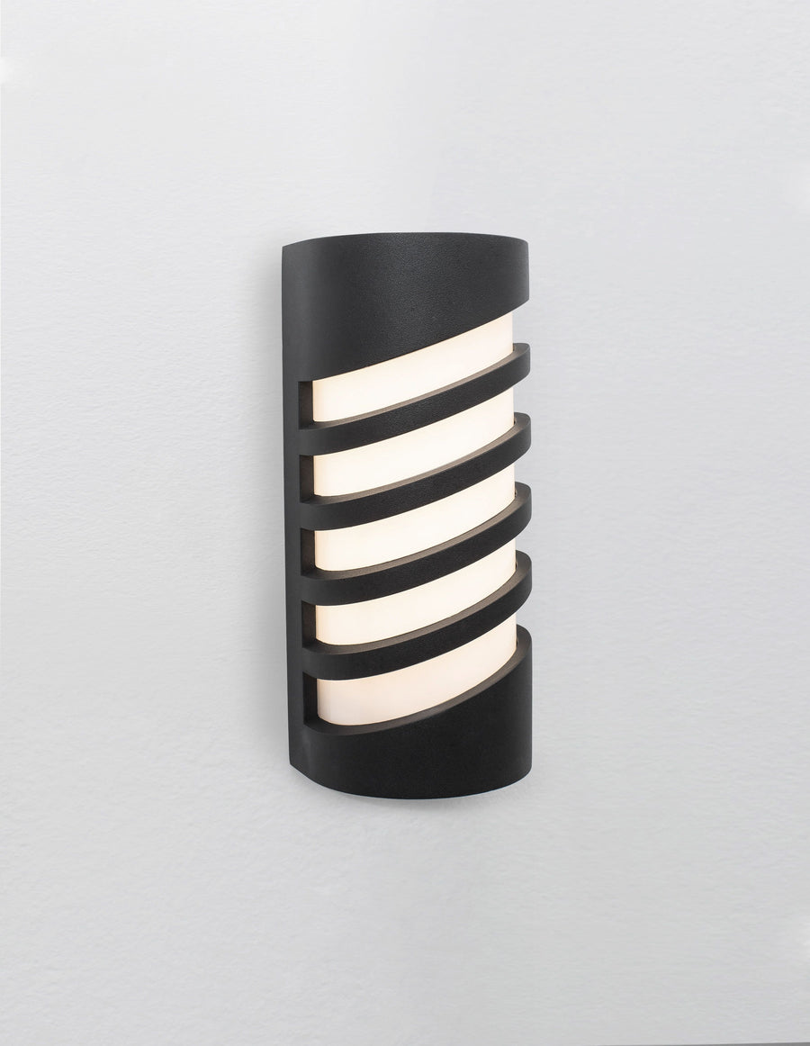 Luminaire allumé de face, lumière chaude traversant le diffuseur entre les lames.