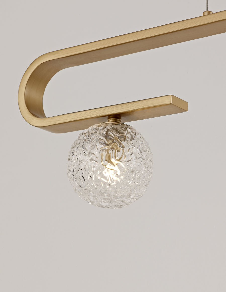 Détail rapproché du bras recourbé doré et de la sphère en verre martelé