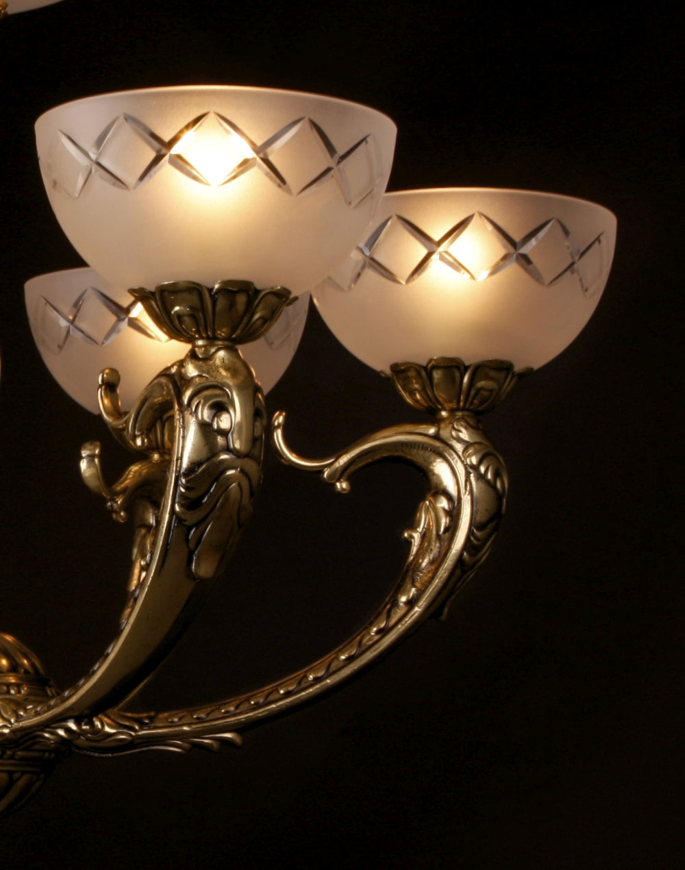 Détail des bras ouvragés dorés et des coupelles en verre dépoli à motifs losangés