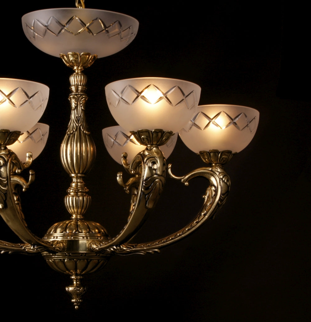 Vue rapprochée du lustre, bras sculptés dorés et coupelles givrées allumées