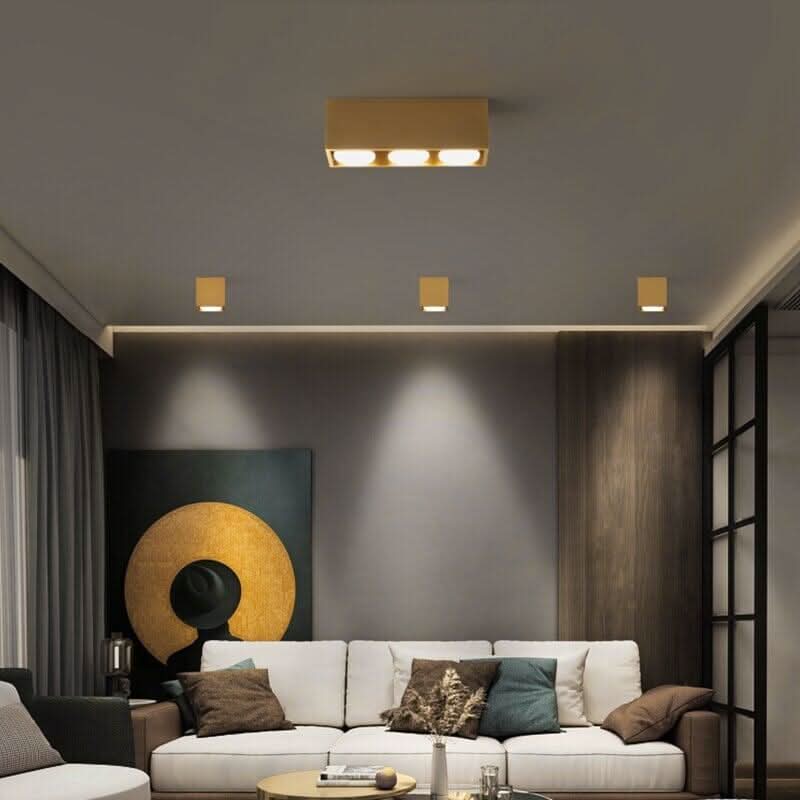 Plafonnier design doré Zephyr Sky allumé au-dessus d'un canapé de salon, ambiance moderne – Designix.fr
