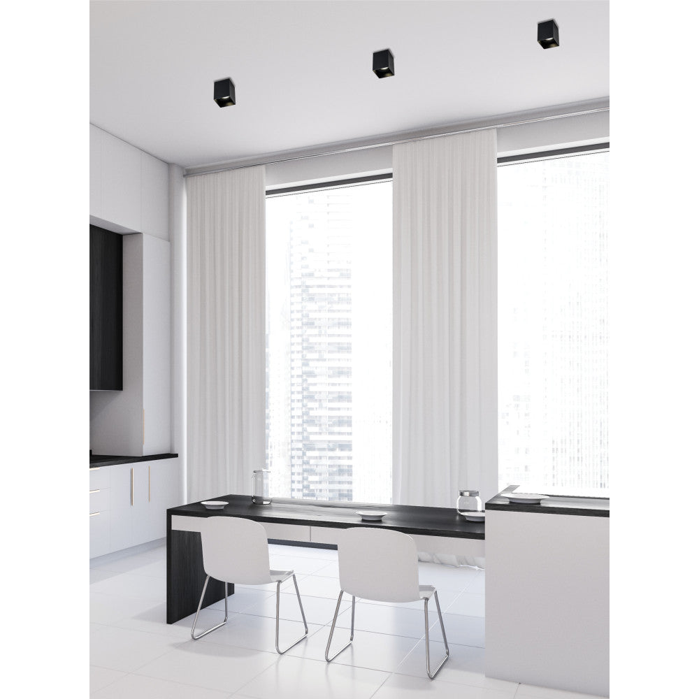 Vue en enfilade de trois plafonniers noirs au plafond, salle à manger moderne.
