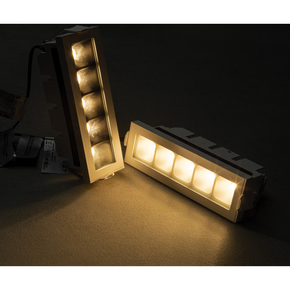 Vue rapprochée de deux luminaires encastrables éclairés, un vertical et un incliné.