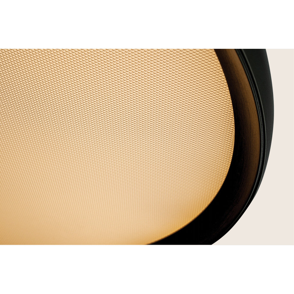 Gros plan sur la surface micro-perforée et l'anneau or brillant du luminaire