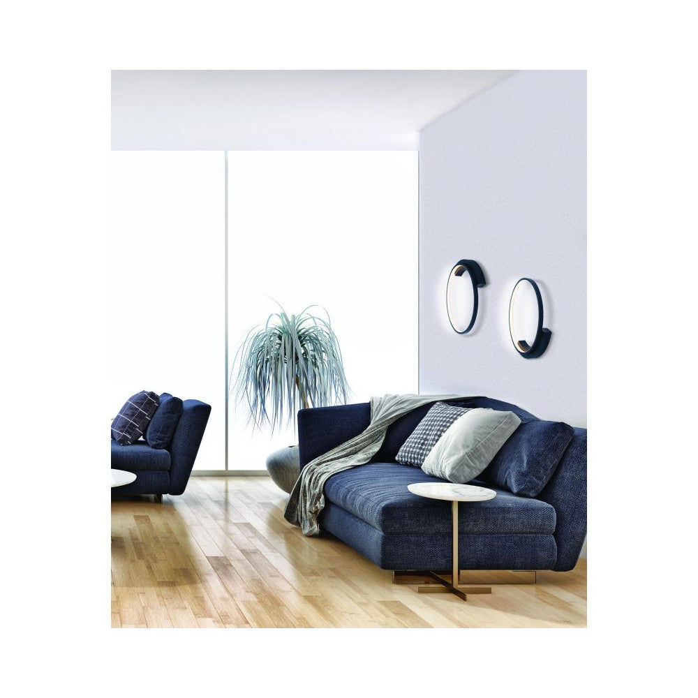Mise en ambiance dans un salon avec canapé bleu et deux appliques murales allumées.