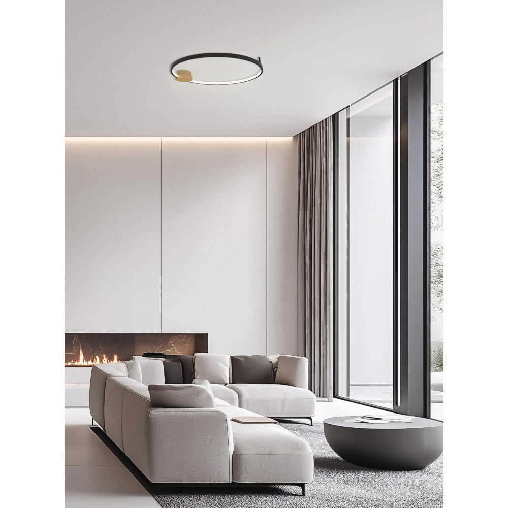 Vue du luminaire annulaire allumé au plafond d'un séjour contemporain avec cheminée