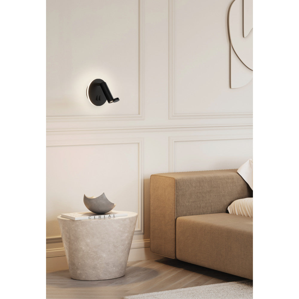 Mise en ambiance dans un salon, applique noire allumée sur mur à moulures beiges