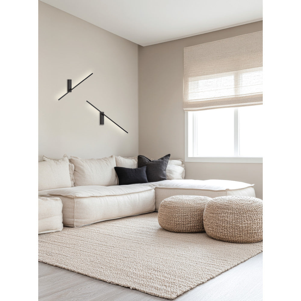 Mise en ambiance : deux appliques murales noires éclairant un canapé beige près d'une fenêtre