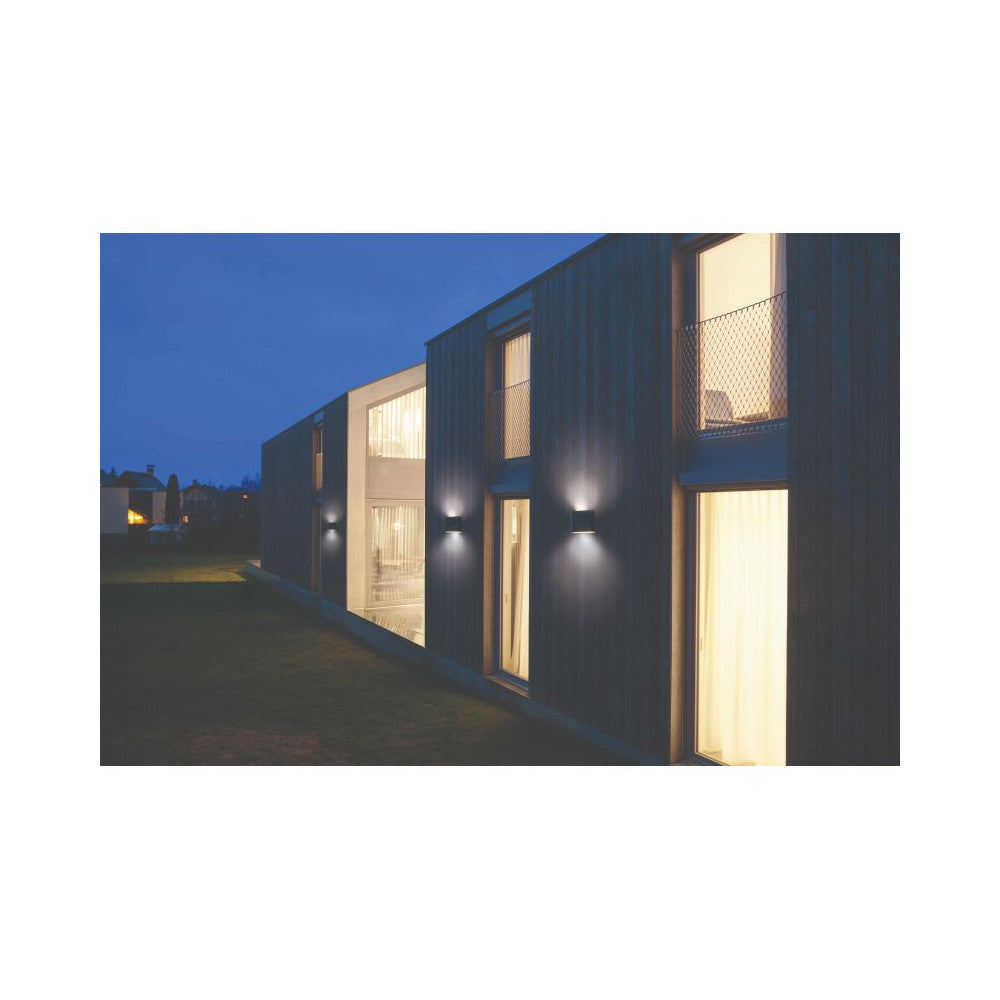 Mise en ambiance nocturne : deux appliques graphites éclairant la façade sombre d'une maison moderne