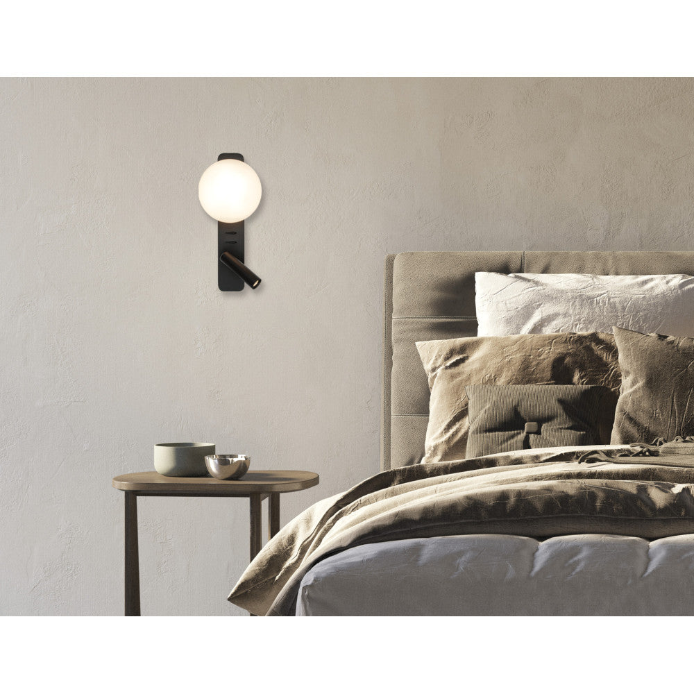 Vue en situation, applique allumée éclairant un mur et un lit