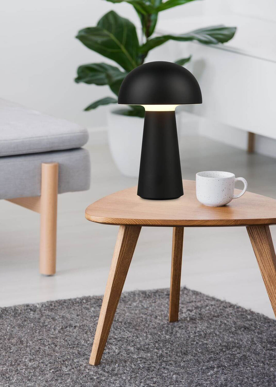 Vue rapprochée de la lampe allumée sur la table, intérieur clair et végétal