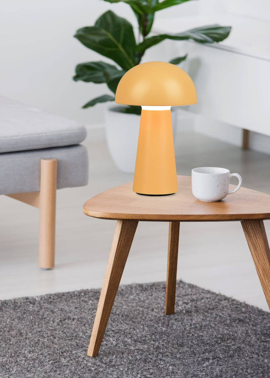 Vue rapprochée du luminaire jaune sur la table, intérieur clair et plante verte