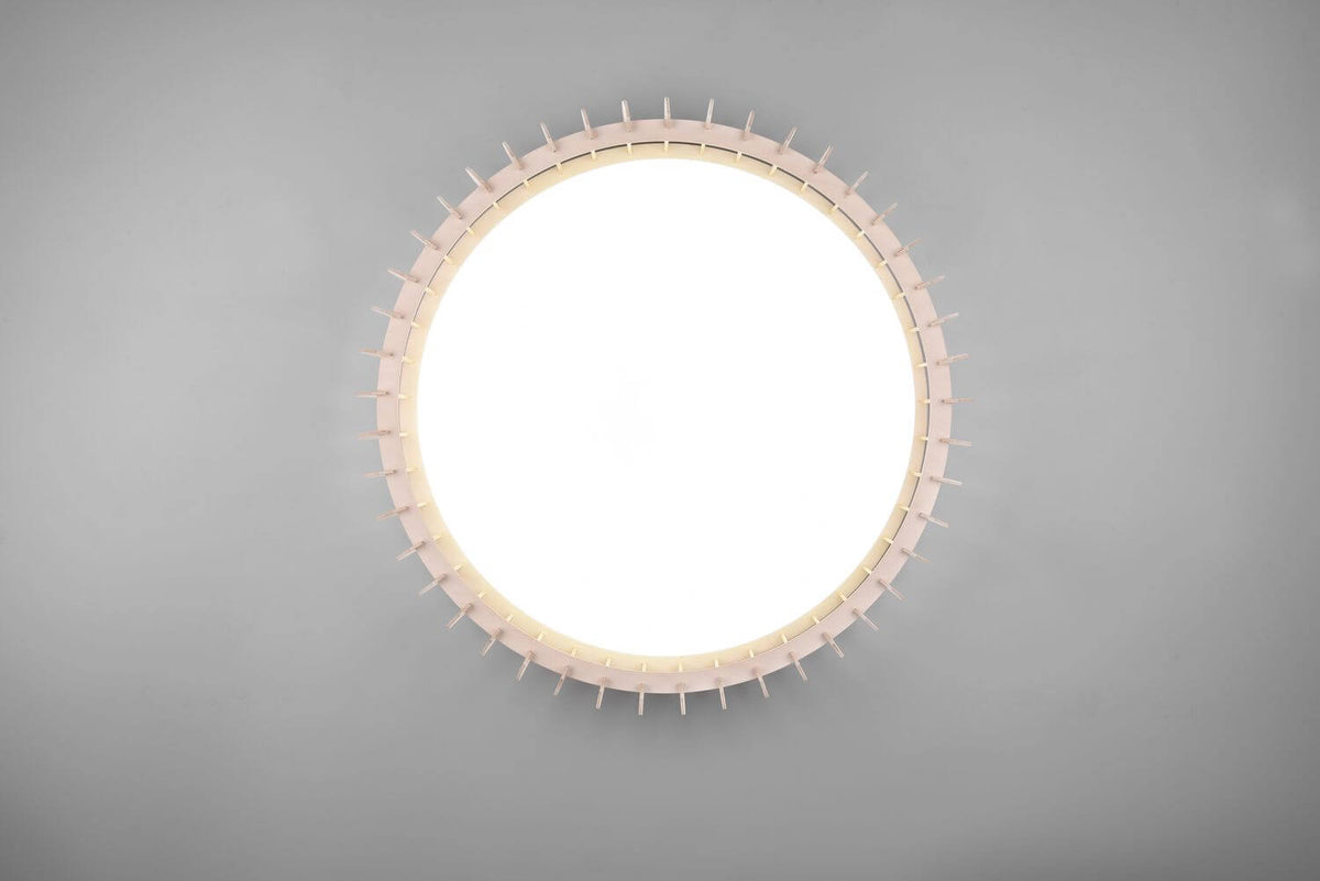 Face inférieure du plafonnier allumé, disque lumineux central et picots régulièrement répartis.