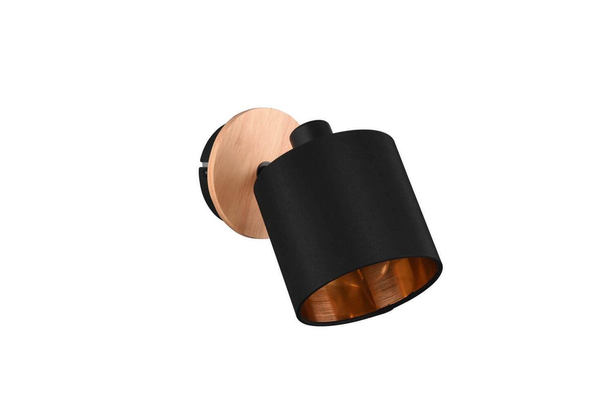 Spot orientable noir vu de trois quarts, intérieur cuivré et embase en bois naturel.