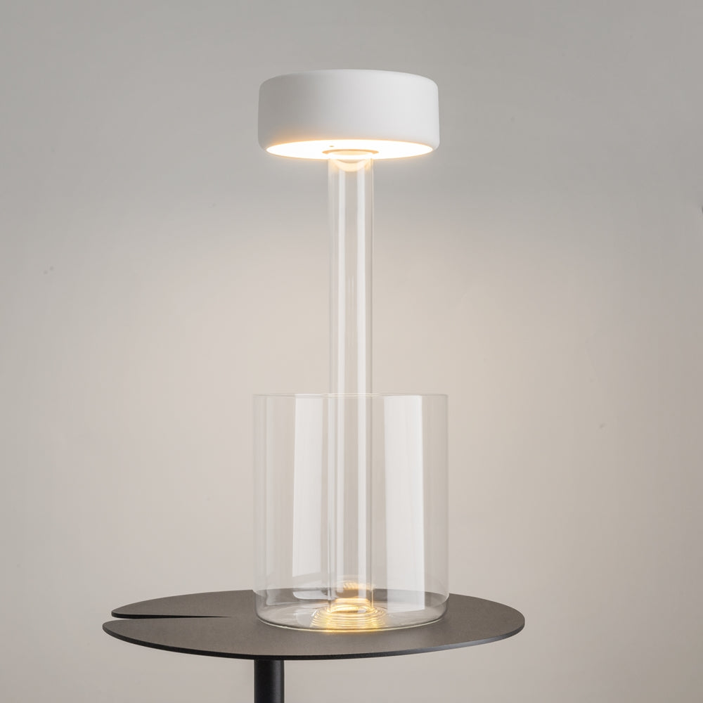 Lampe allumée posée sur une table ronde sombre, halo chaud diffus