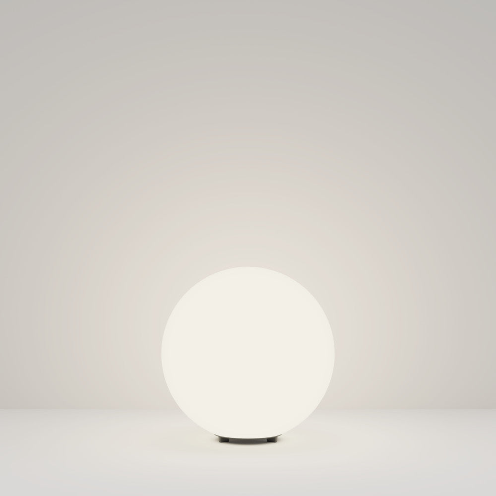 Vue d'ensemble du luminaire sphérique blanc éclairé, posé sur fond neutre