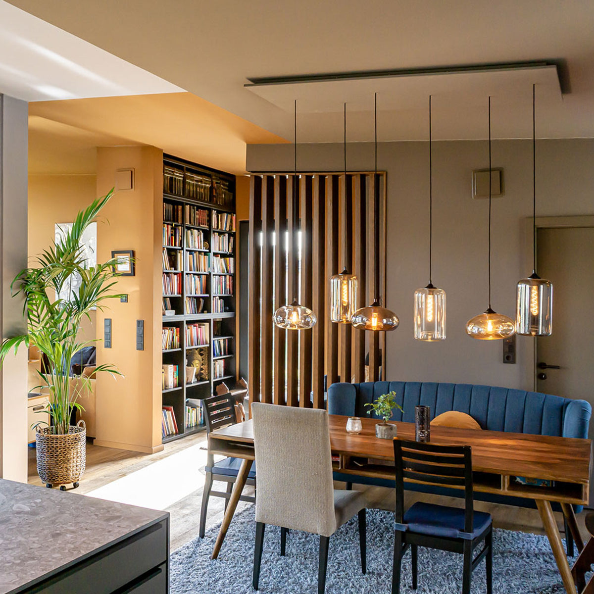 Suspensions allumées au-dessus d'une table à manger en bois dans un intérieur moderne.