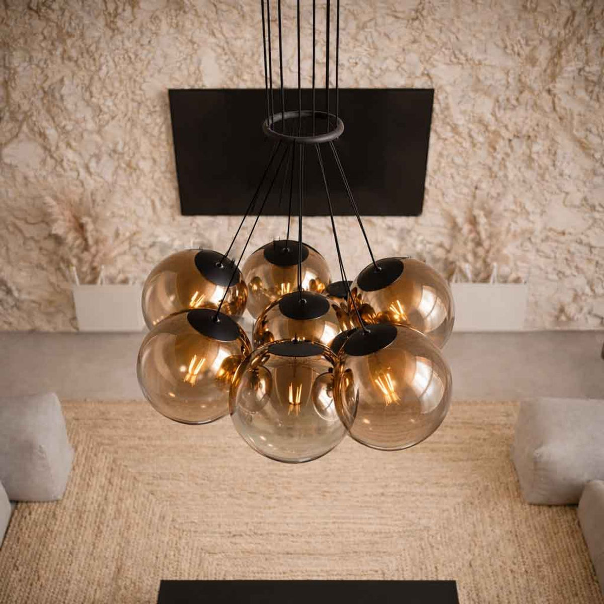 Vue de dessous des sept globes cuivrés suspendus devant un mur en pierre claire