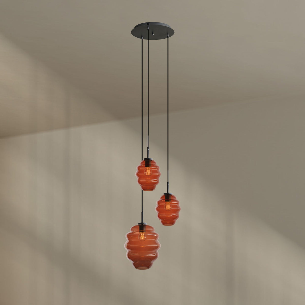 Détail produit : trois verres ambrés striés de tailles différentes sur fond beige uni.