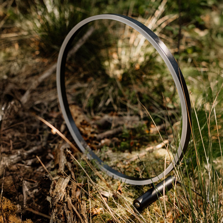 Anneau noir du luminaire photographié en extérieur, posé au sol dans les herbes sèches