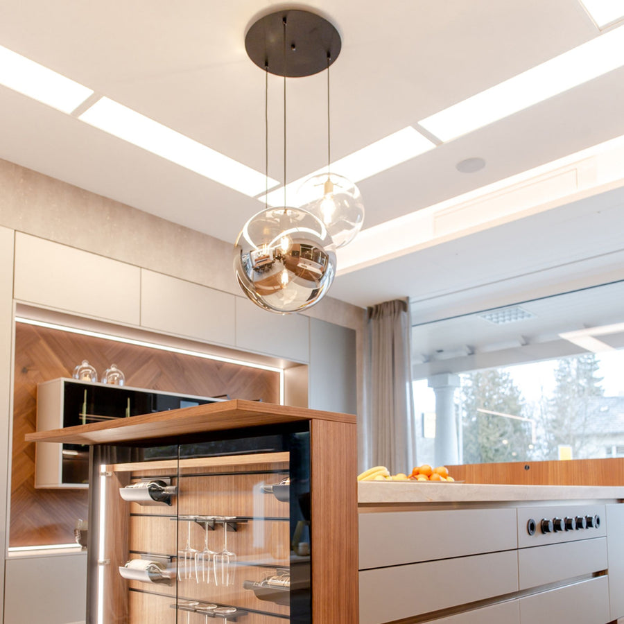 Au-dessus de l'îlot de cuisine, trois globes en verre aux reflets cuivrés et transparents.