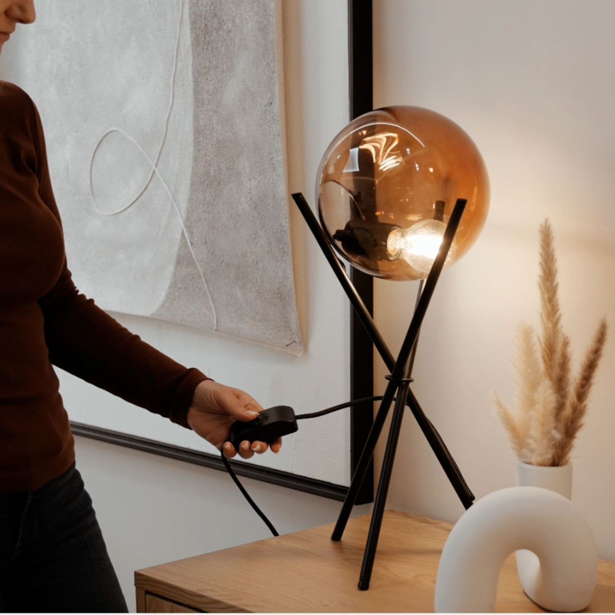 Personne réglant le variateur en ligne d'une lampe noire à globe ambré allumé