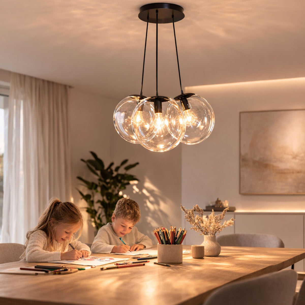 Enfants dessinant sous la suspension aux trois globes en verre transparent