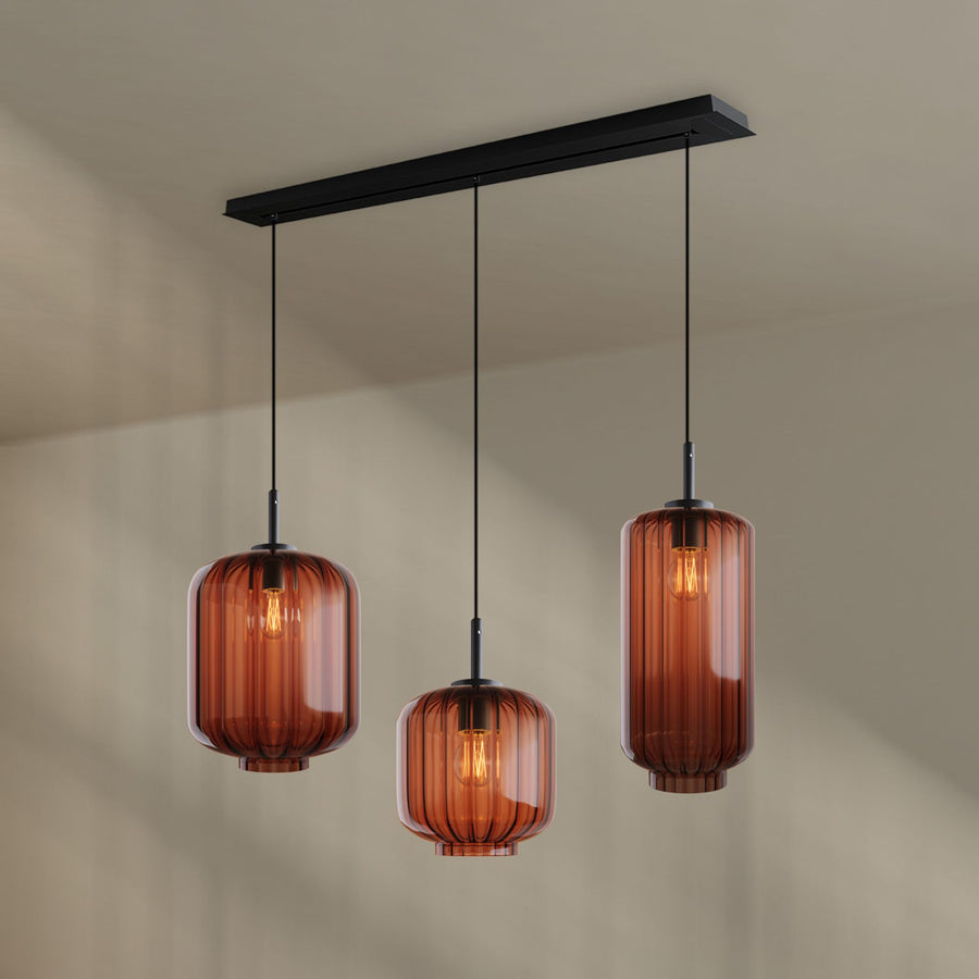 Vue de face du luminaire, trois verres ambrés striés suspendus sous une barre noire
