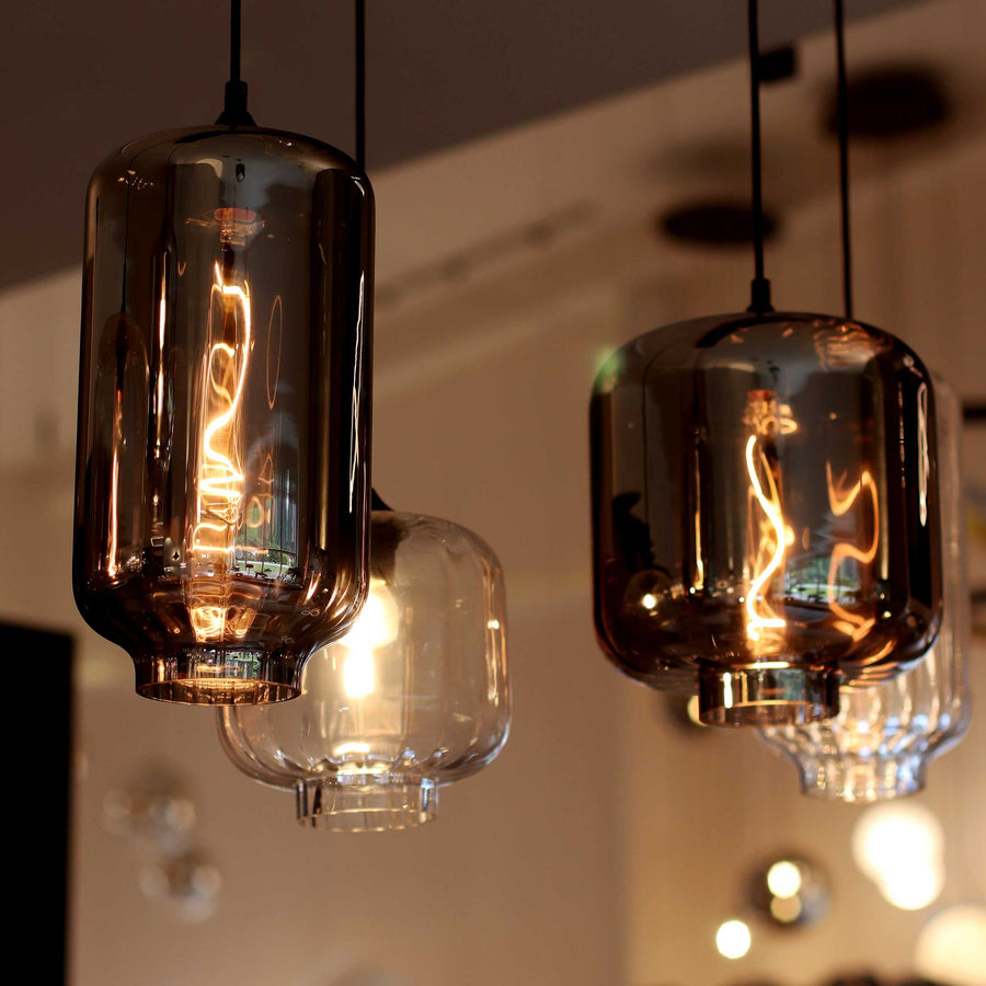 Détail rapproché de suspensions aux verres fumés et ambrés, ampoules à filament apparentes allumées.