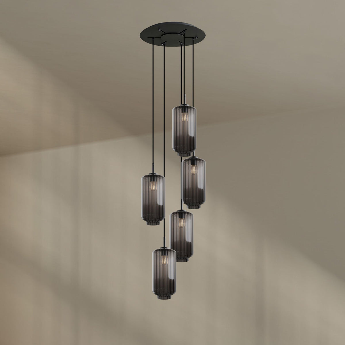 Cinq suspensions aux verres fumés gris transparents devant un mur beige