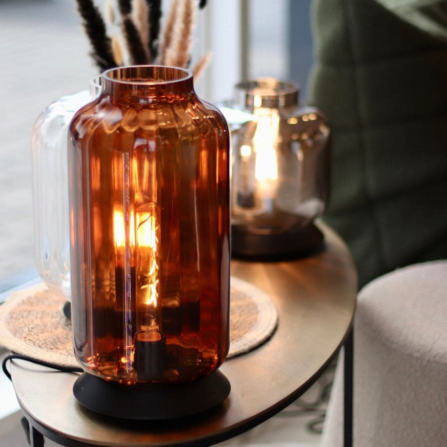 Gros plan de face sur la lampe ambre allumée, ampoule visible à travers le verre