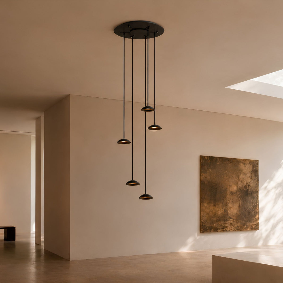 Vue d'ensemble d'une suspension noire à cinq lumières dans un intérieur clair.